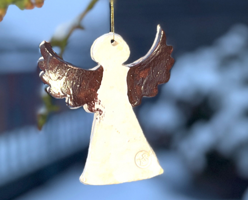 Tonengel hängt im Schnee an einem Baum