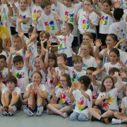 lachende Kinder sitzen winkend auf dem Boden